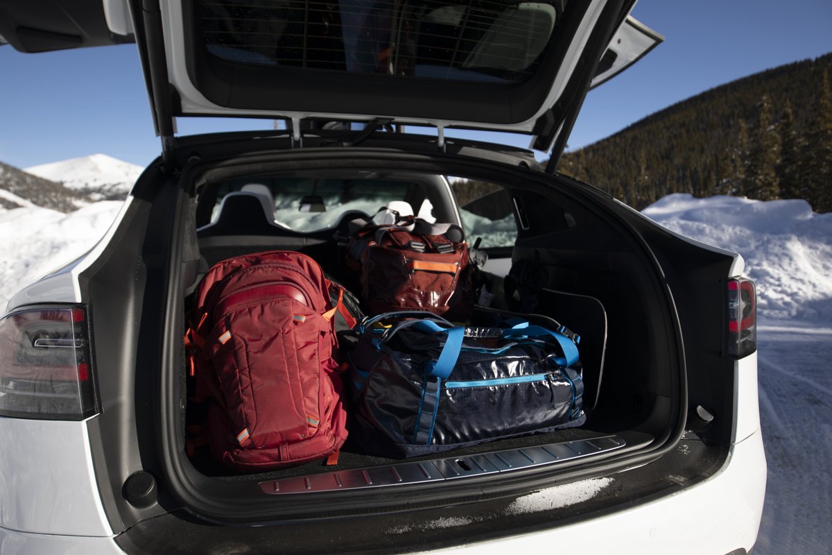 Some camping bags in the back of an open trunk of a Tesla. There’s snow. Presumably they’re going camping.