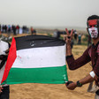Two young men with painted faces hold a Palestinian flag