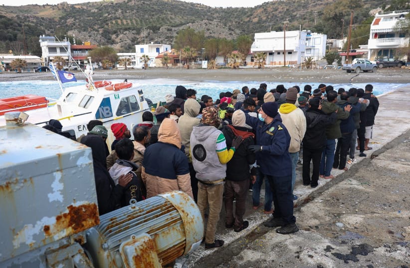 Migrants stand in line as a Greek coast guard officer counts them at the port of Kaloi Limenes, on the island of Crete, Greece, February 21, 2026.