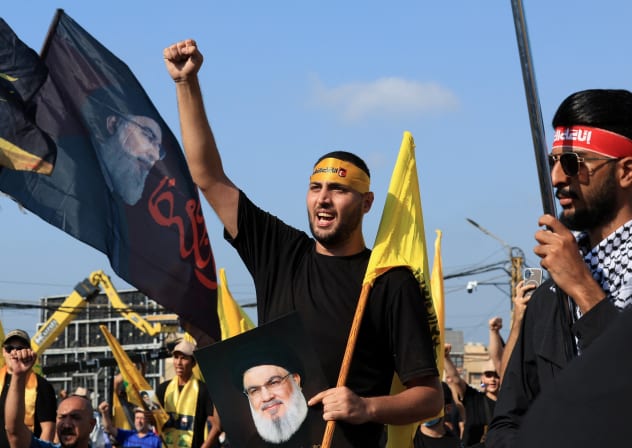 A Hezbollah supporter holds an image of late Hezbollah leader Hassan Nasrallah at a ceremony held by Hezbollah to commemorate the first anniversary of Nasrallah's killing by Israel, on the outskirts of Beirut, Lebanon, September 27, 2025