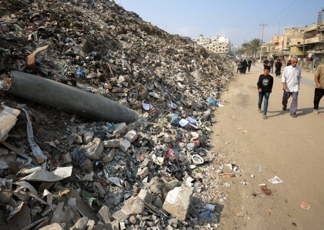 Palestinians walk past the remains of a munition, during a ceasefire between Israel and Hamas, in Gaza City, November 11, 2025