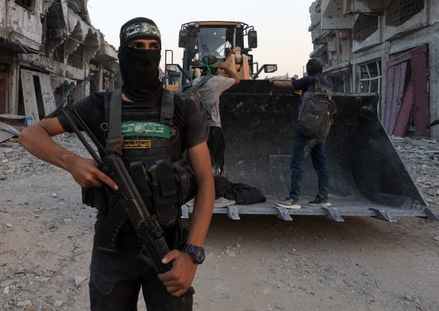 A Palestinian Hamas terrorist stands next to heavy machinery, after Hamas said that it found the body of an Israeli hostage soldier on Tuesday and prepares to return it to Israel through the Red Cross, in Gaza City, November 4, 2025.