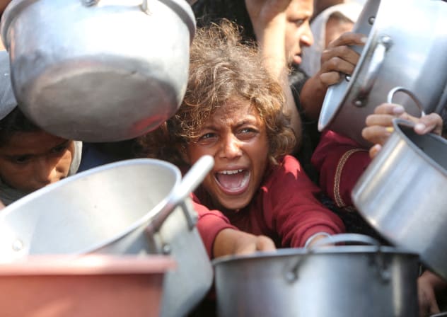 : A child reacts surrounded by pots as Palestinians wait to receive food from a charity kitchen in Khan Younis, southern Gaza Strip, August 21, 2025.