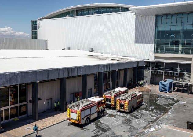 Emergency services vehicles are seen parked near the departure terminal of the Cape Town International Airport on February 24, 2026 following reports of a fire that broke out on February 24, 2026.