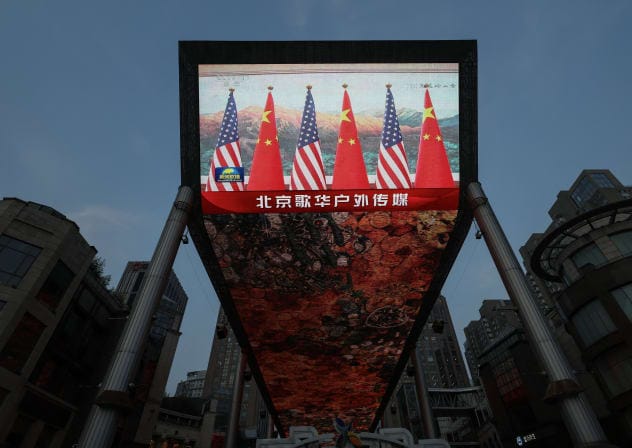 A giant screen at a shopping area shows news footage of national flags of China and the United States during a meeting between Chinese President Xi Jinping and US President Donald Trump at the Great Hall of the People, in Beijing, China May 14, 2026.