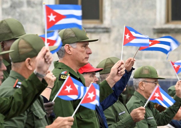 Cuba's President Miguel Diaz-Canel waves a Cuban flag alongwith others during a march outside the U.S. Embassy to protest against what they denounce as U.S. aggression in the region, following the capture of Venezuelan leader Nicolas Maduro and the killing of Cuban soldiers on January 16, 2026.