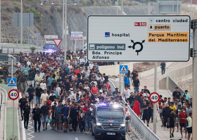 Police officers and Spanish soldiers escort a big group of migrants to the border to take them out of Spain, after mass crossings of migrants on foot and by sea from Morocco into Spanish territory, in Ceuta, Spain, August 1, 2026.
