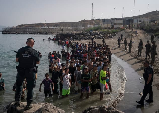 Members of the Guardia Civil USECIC guard migrants on Tarajal beach after crossing the border between Spain and Morocco on July 31, 2026 in Ceuta, Spain.
