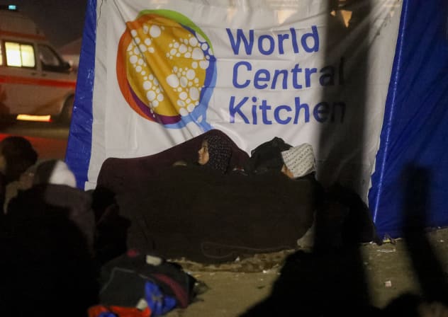 People sit in front of a World Central Kitchen in Deir al-Balah, Gaza Strip, on January 26, 2025.