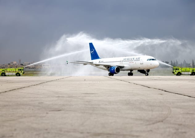 A Syrian Airlines passenger jet, the first aircraft to land at Aleppo airport after it was shut during the offensive that toppled president Bashar al-Assad, receives a water salute upon arrival on March 18, 2025.