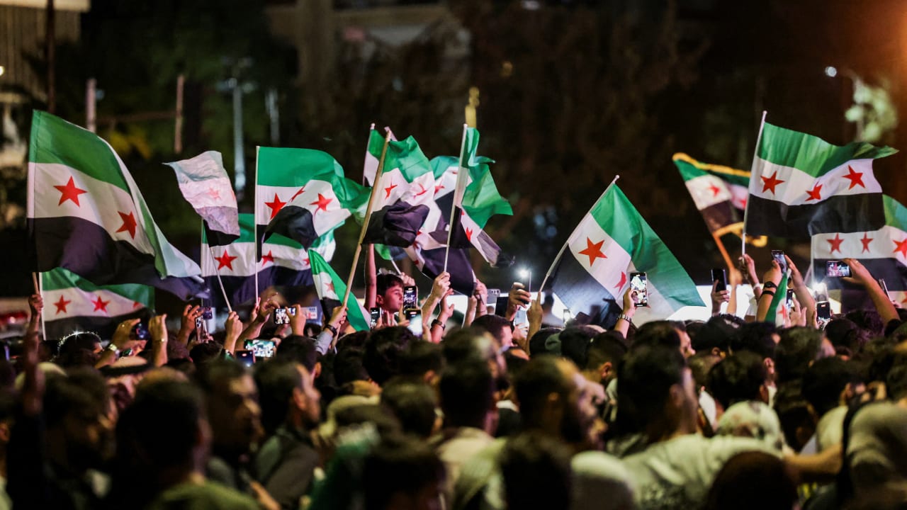People wave Syrian flags as they gather at Umayyad Square in Damascus to watch a broadcast of Syrian President Ahmed Al-Sharaa delivering a speech at the United Nations, in Syria, September 24, 2025.