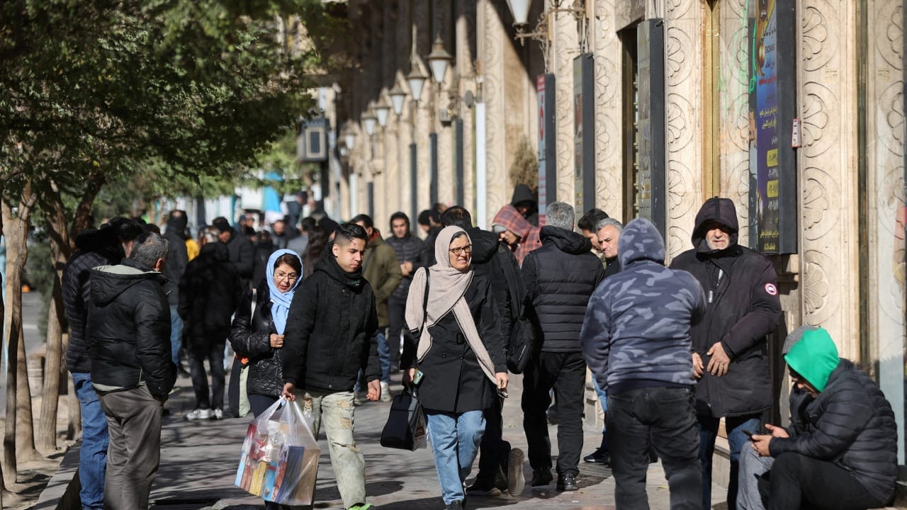 People walk past stores as the value of the Iranian Rial drops, in Tehran, Iran, December 30, 2025.