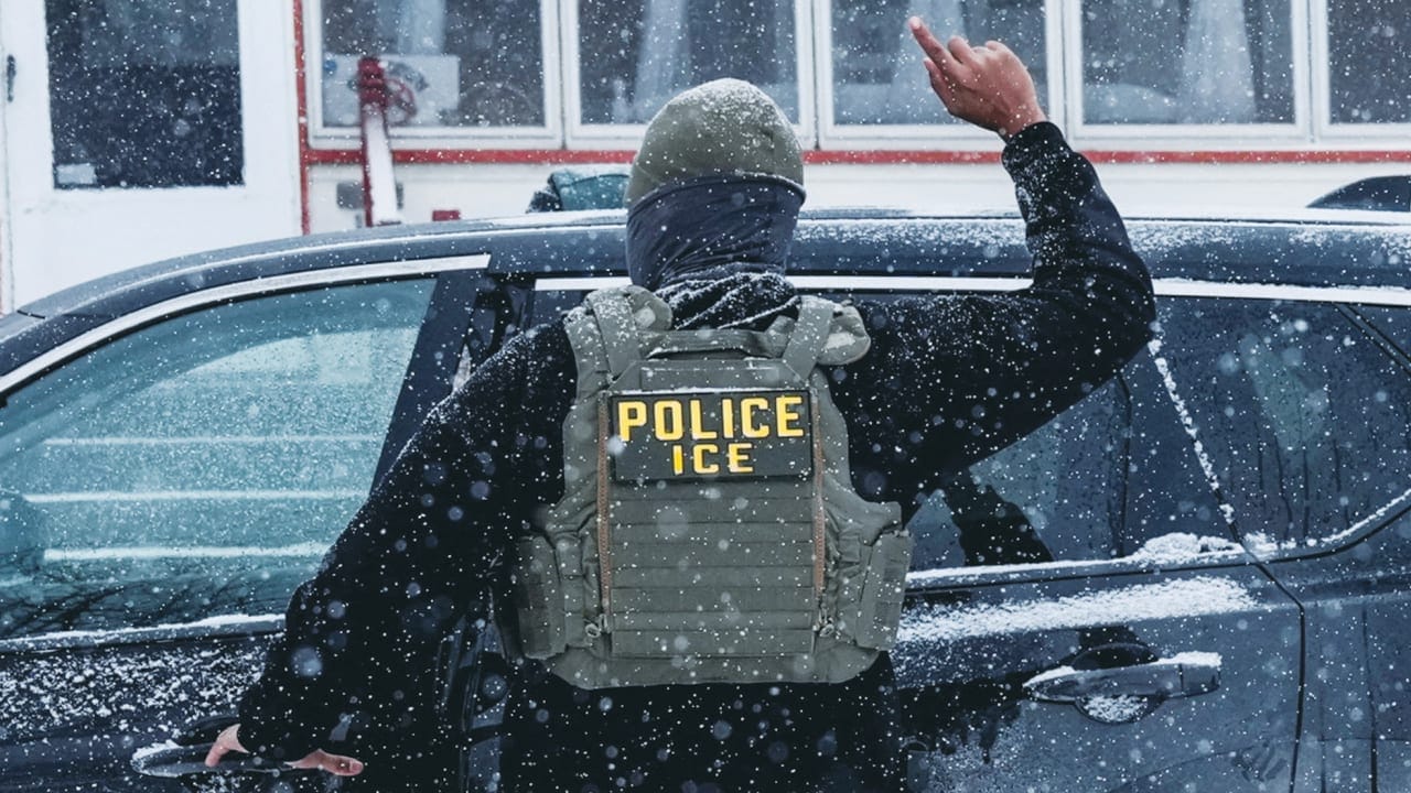 An immigration and Customs Enforcement (ICE) agent raises a finger moments after detaining a man during an immigration raid, on Sunday in Minneapolis.