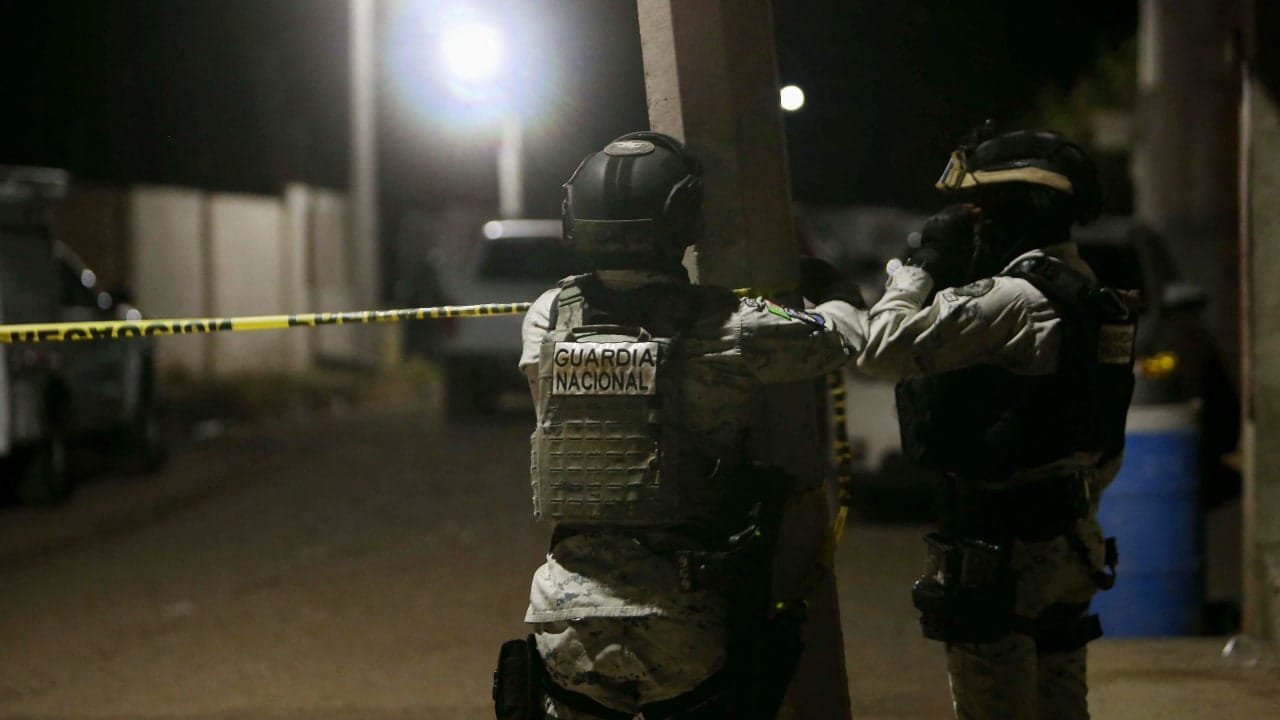 Members of the National Guard install a yellow police line at the crime scene where at least 11 people were killed and 12 more wounded during an armed attack at a football field in Salamanca, Guanajuato state, Mexico, on January 25, 2026. 