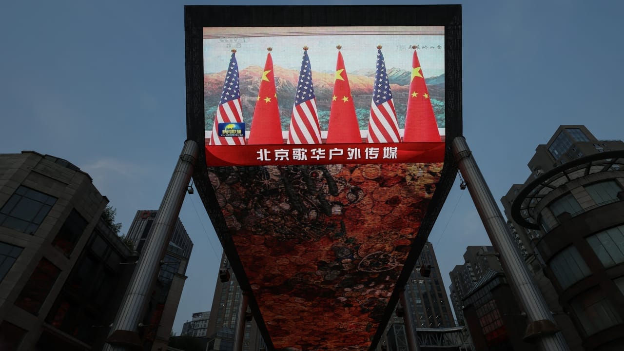 A giant screen at a shopping area shows news footage of national flags of China and the United States during a meeting between Chinese President Xi Jinping and US President Donald Trump at the Great Hall of the People, in Beijing, China May 14, 2026.