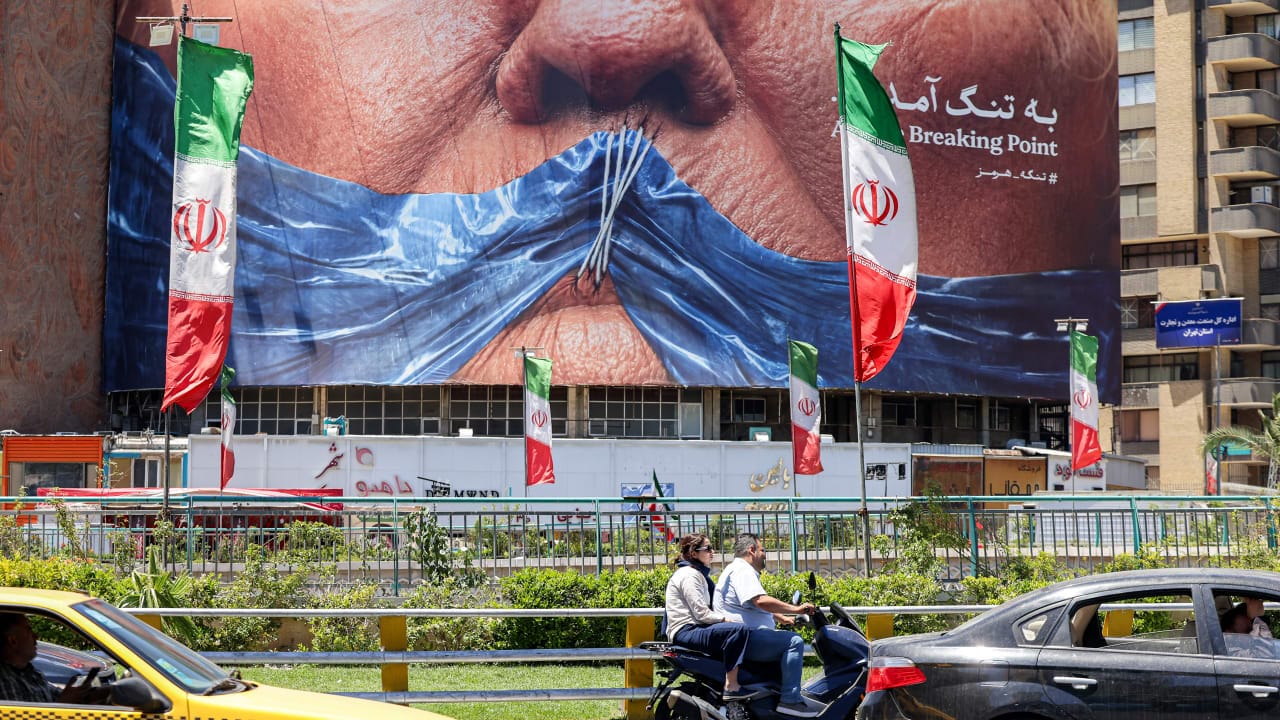 Motorists drive their vehicles past a political billboard featuring US President Donald Trump and the Strait of Hormuz along Valiasr Square in Tehran on May 26.