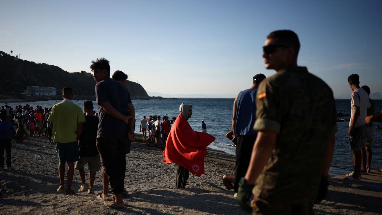 Migrants stand on a beach in Ceuta, following mass crossings of migrants on foot and by sea from Morocco into Spanish territory, in Ceuta, Spain, August 2, 2026.