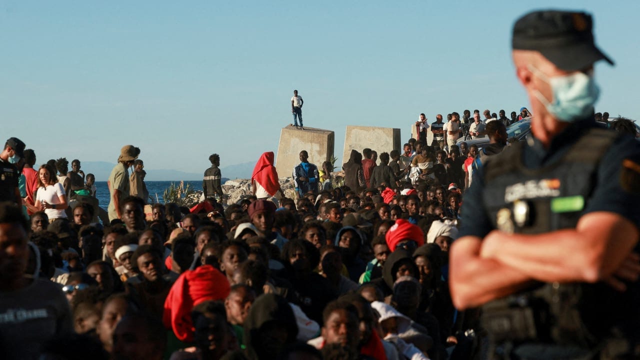 Migrants wait in line to receive food and beverage from the Red Cross, following mass crossings of migrants on foot and by sea from Morocco into Spanish territory, in Ceuta, Spain, August 3, 2026. 