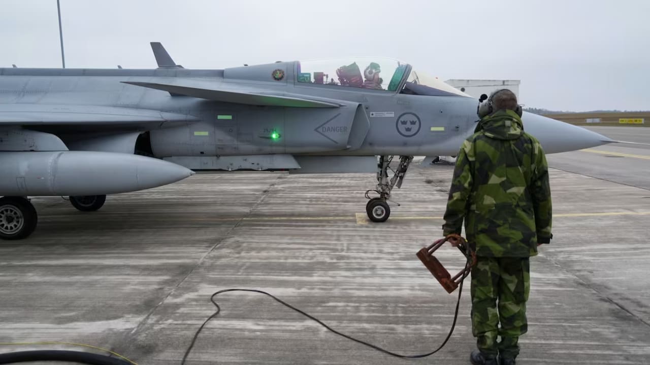 A member of the ground crew of the Swedish Air Force stands next to a JAS 39 Gripen fighter aircraft in Kallinge, Sweden, December 16, 2025.
