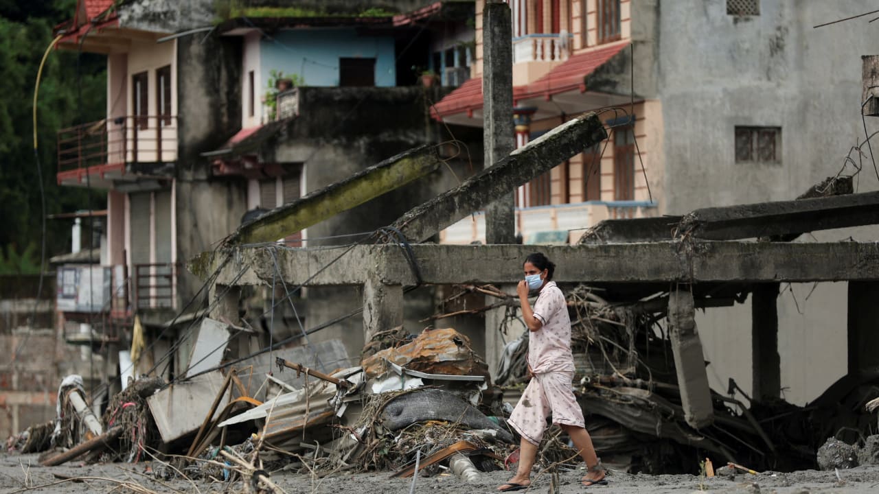 A woman walks past destroyed buildings after flash floods and mudslides, in Devighat, Nuwakot district, Nepal, August 29, 2026.