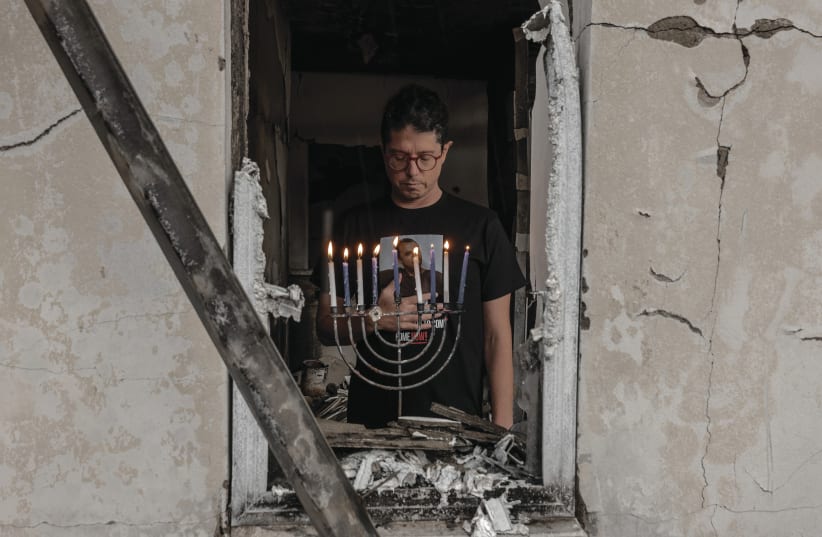  ‘A POWERFUL reminder of the resilience and hope that dwell within us all.’ Yuval Haran, a resident of Kibbutz Be’eri, returned to his home this week and lit a hanukkiah that was retrieved from the rubble.  (photo credit: CHEN SCHIMMEL)