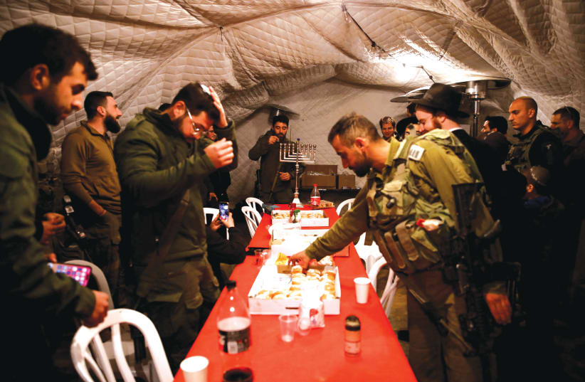  SOLDIERS GATHER to celebrate the first day of Hanukkah, near the Israeli-Lebanon border, last week. (photo credit: Shir Torem/Reuters)