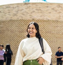 Students standing on campus, talking and smiling.