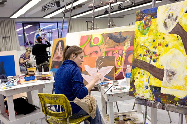 Student seated at easel working on a painting