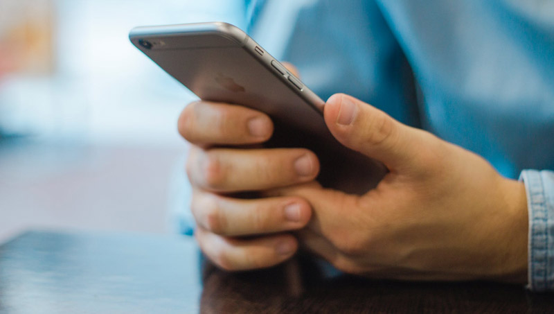 Close up shot of a man's hands holding an iPhone