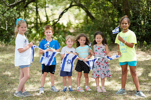 Preschool and school age kids holding a string with Israeli flags