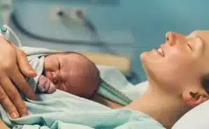 אישה לאחר לידה עם התינוק עליה