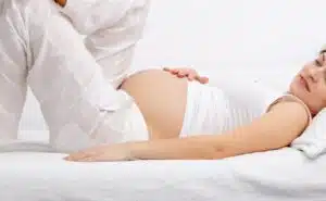 אישה בהריון מחזיקה את הבטן ונחה על הספה