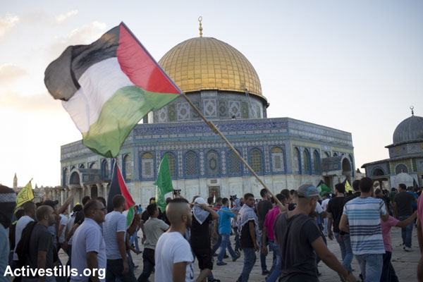 Palestinian youth hold a Palestinian flag outside the Aqsa Mosque in the Haram al-Sharif/Temple Mount compound, East Jerusalem. (Oren Ziv/Activestills.org)