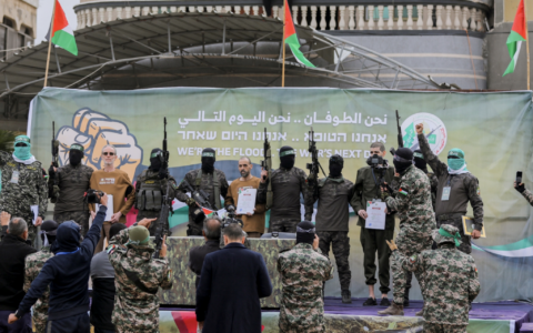Israeli hostages stand on stage flanked by Hamas militants during the official handover in Gaza, Gaza Strip, on February 8, 2025. (Youssef Alzanoun / Middle East Images / Middle East Images via AFP)