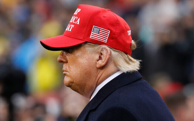US President Donald Trump wears a red hat as he stands on the field before the Army-Navy college football game in Philadelphia, on December 14, 2019. (AP/Jacquelyn Martin) US President Donald Trump wears a red hat as he stands on the field before the Army-Navy college football game in Philadelphia, on December 14, 2019. (AP/Jacquelyn Martin)