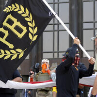 A protester carries a Proud Boys banner while other members start to unfurl a large US flag in front of the Oregon State Capitol in Salem, Oregon, September 7, 2020 (AP/Andrew Selsky).