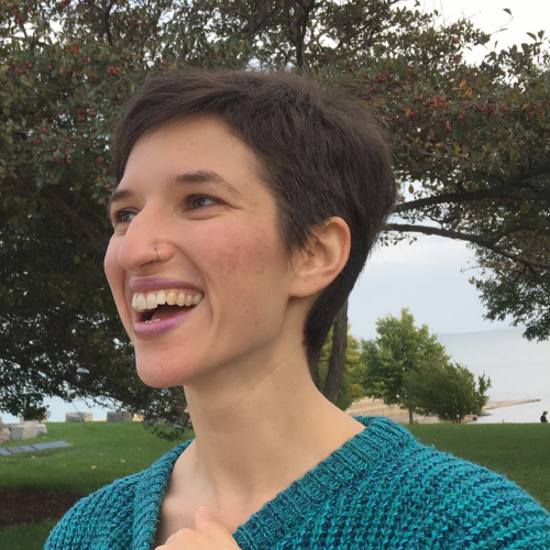 Arielle looks off to the left and smiles. She is wearing a blue sweater.