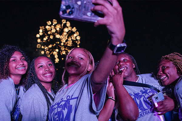 Students taking selfie while watching fireworks