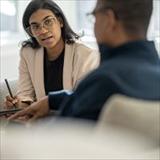 A health professional is taking notes while meeting with a patient