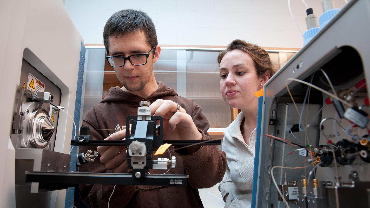 Two graduate students working in lab with equipment