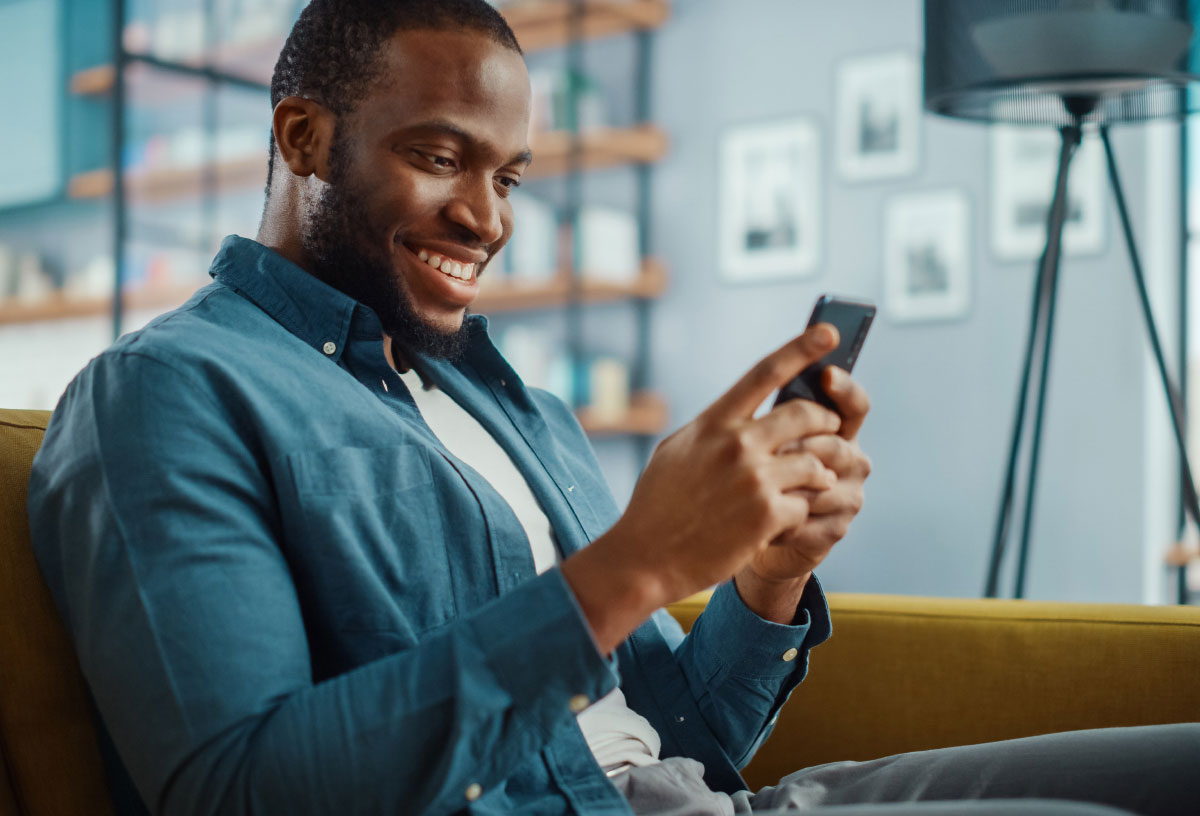 a smling man holding his mobile phone; Knect - Skrill Loyalty program
